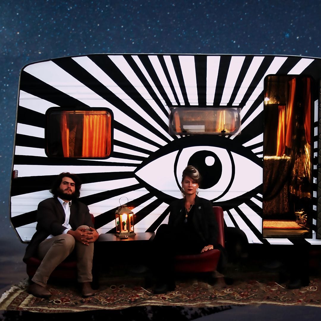 Les deux comédiens sont assis devant leur caravane.