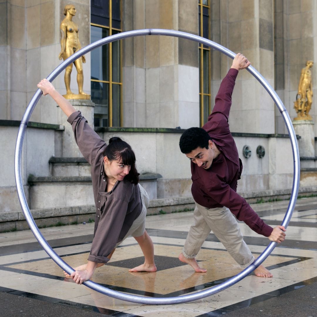 Les deux artistes sont en équilibre sur un cerceau.
