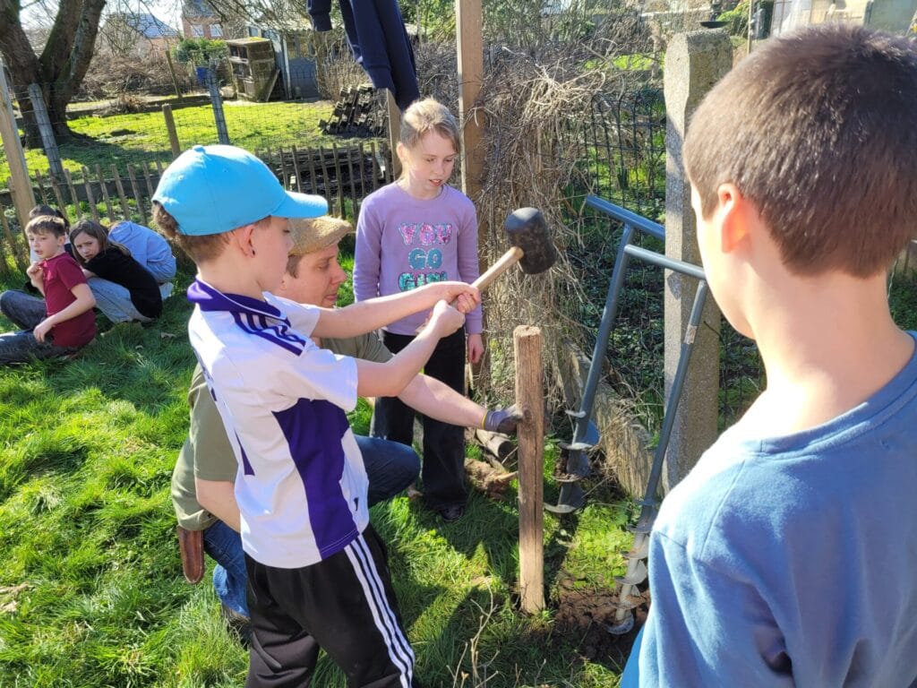 De jeunes enfants installent le premier piquet pour la création d'un abri à hérissons